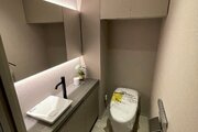 大きな鏡と独立手洗い器を備えたスタイリッシュなトイレ空間です！上部には扉付きの吊戸棚があり、トイレットペーパーや掃除用品を隠してスッキリ収納できますね♪ゲストも快適に利用できる上質な設備です！