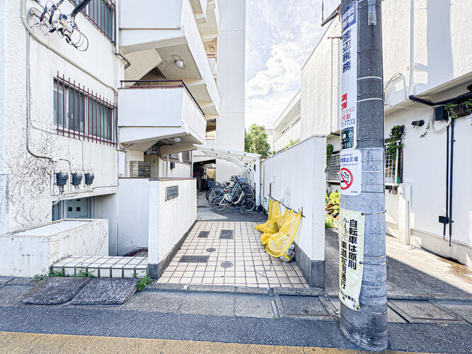平坦なタイル敷きのアプローチが広がるマンションのエントランス前です！奥には駐輪スペースも確保されており、自転車での通勤や日々のちょっとしたお買い物時にもスムーズに出入りができて大変便利です♪