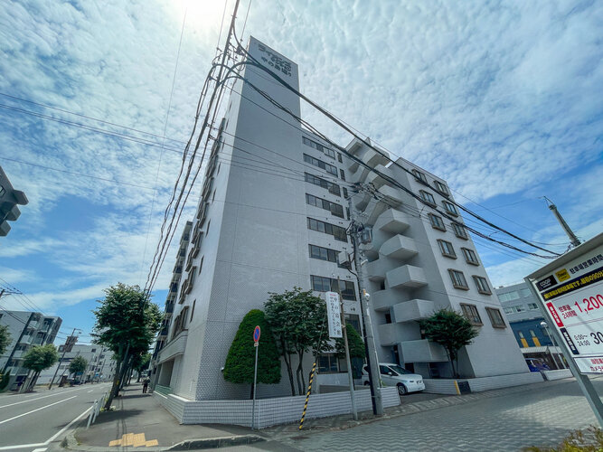 青空に映えるスタイリッシュで落ち着いた雰囲気のマンション外観です！周辺は平坦な道のりが多く、毎日のお買い物やお散歩もスムーズに楽しめます。しっかりとした造りで、日々の暮らしに安心感を与えてくれます♪